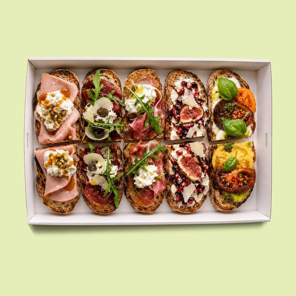 Mixed Italian gourmet crostini platter with heirloom tomato and burrata, fig and pomegranate burrata, prosciutto and rocket, bresaola with truffle and parmesan, and mortadella with honey and pistachio.