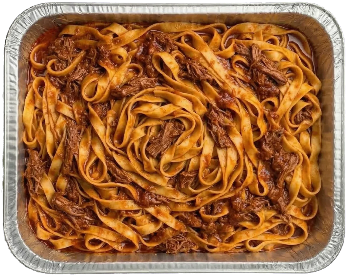 Tagliatelle Pasta in a office catering foil platter with lamb ragu shredded meat and a brown sauce, photographed from above.