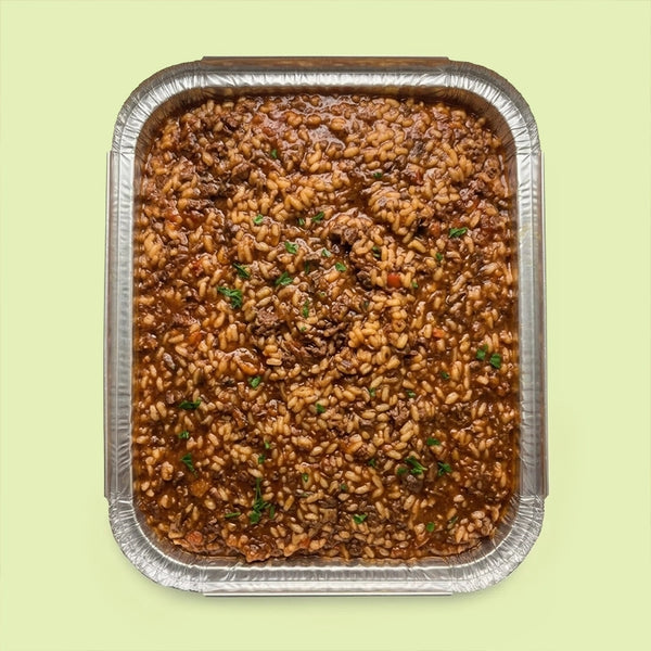 Risotto al Braised Beef Ragù in a catering tray, slow-cooked Arborio risotto with rich braised beef ragù and fresh parsley.