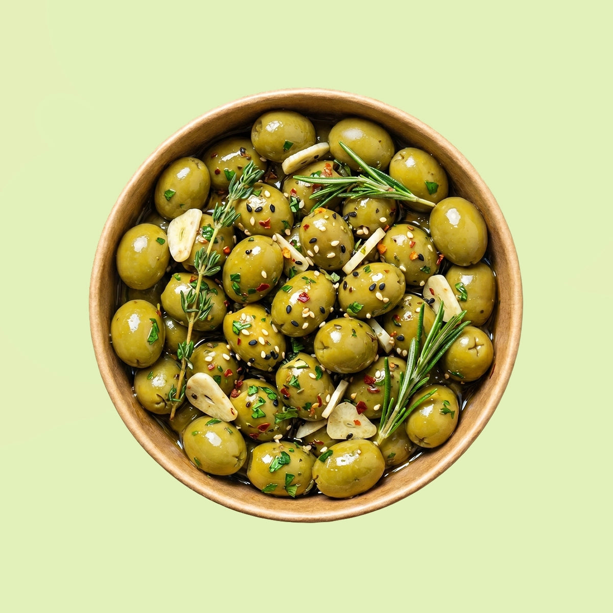 Bowl of marinated green cocktail olives with herbs on a light green background