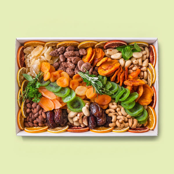 Dried fruit and nut platter with dried orange, blood orange and lemon slices, apricots, dates, kiwi, peach, candied pineapple and ginger, almonds, cashews and Brazil nuts, garnished with fresh herbs.