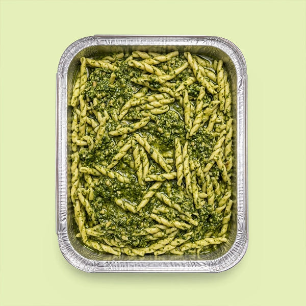 Trofie al Pesto in a catering tray — twisted trofie pasta generously coated in vibrant Ligurian basil pesto.