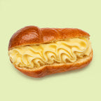 Mini Sicilian baba pastries, syrup soaked and glazed, shown halved to reveal vanilla custard filling.