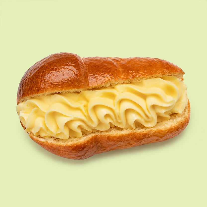 Mini Sicilian baba pastries, syrup soaked and glazed, shown halved to reveal vanilla custard filling.