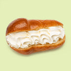 Mini Sicilian baba pastries, syrup soaked and glazed, halved to reveal whipped cream  filling.