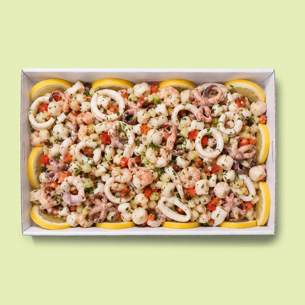 Italian seafood salad platter with calamari rings, baby octopus, prawns, diced tomato and parsley, served on a bed of fresh lemon slices.