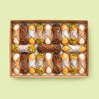 Assorted Italian Cannoli pastries in a box on a light green background