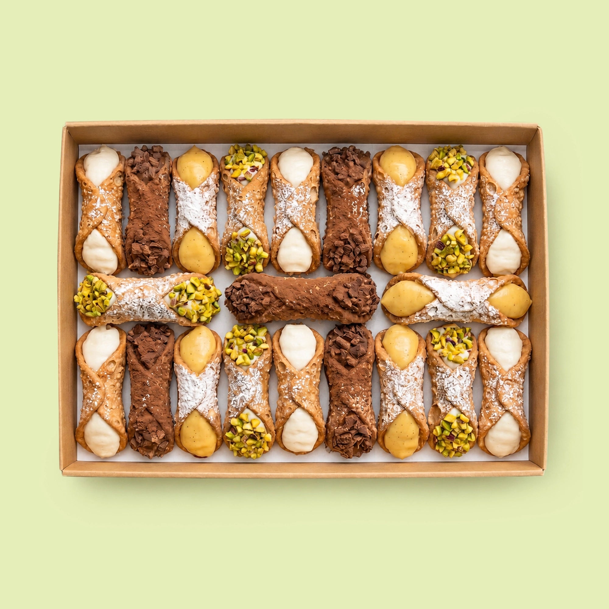Assorted Italian Cannoli pastries in a box on a light green background