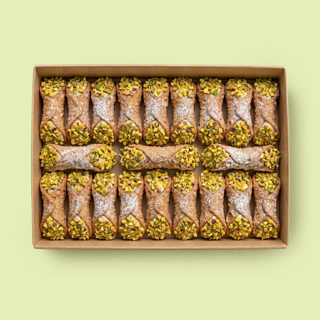 Box of cannoli with pistachios on a light green background
