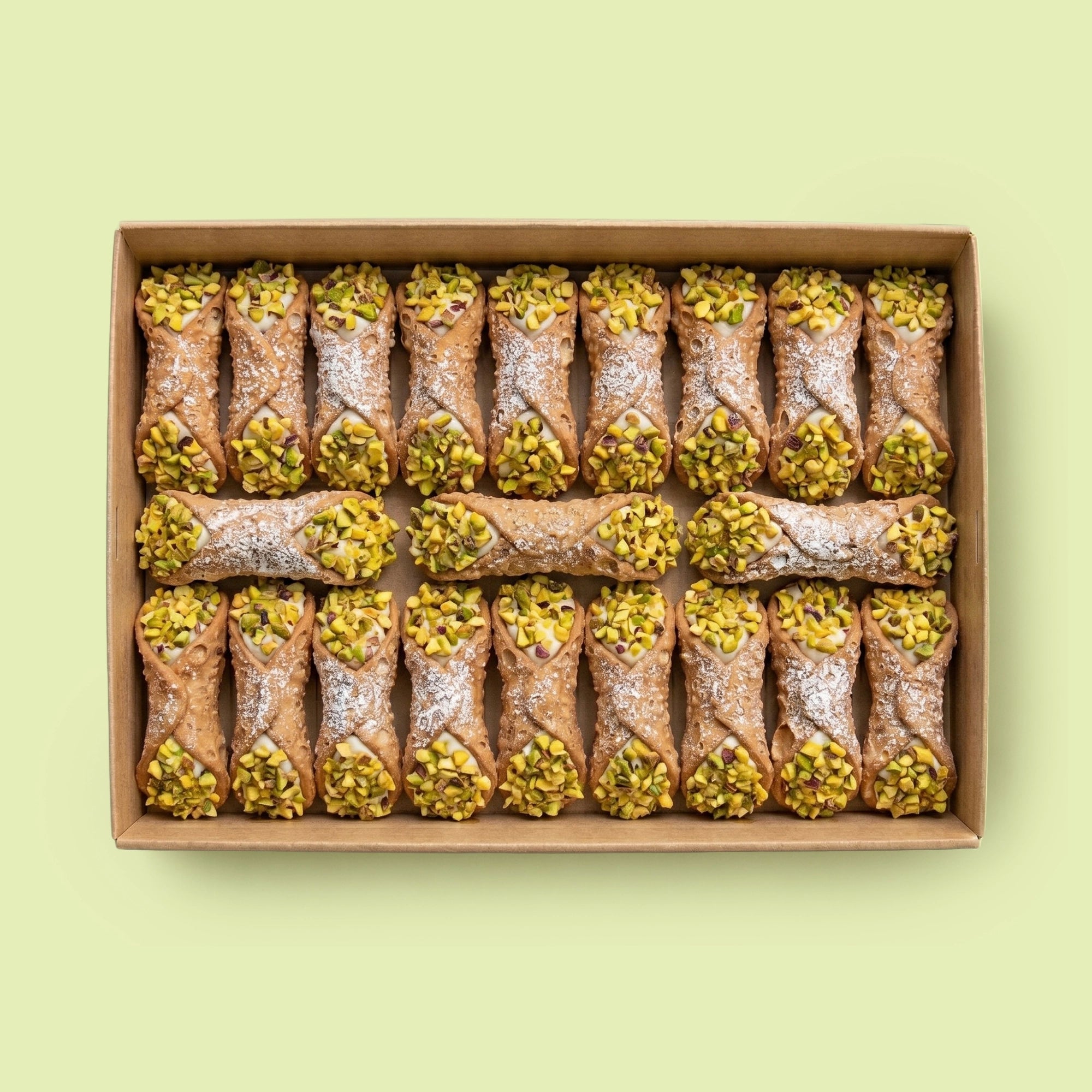 Box of cannoli with pistachios on a light green background