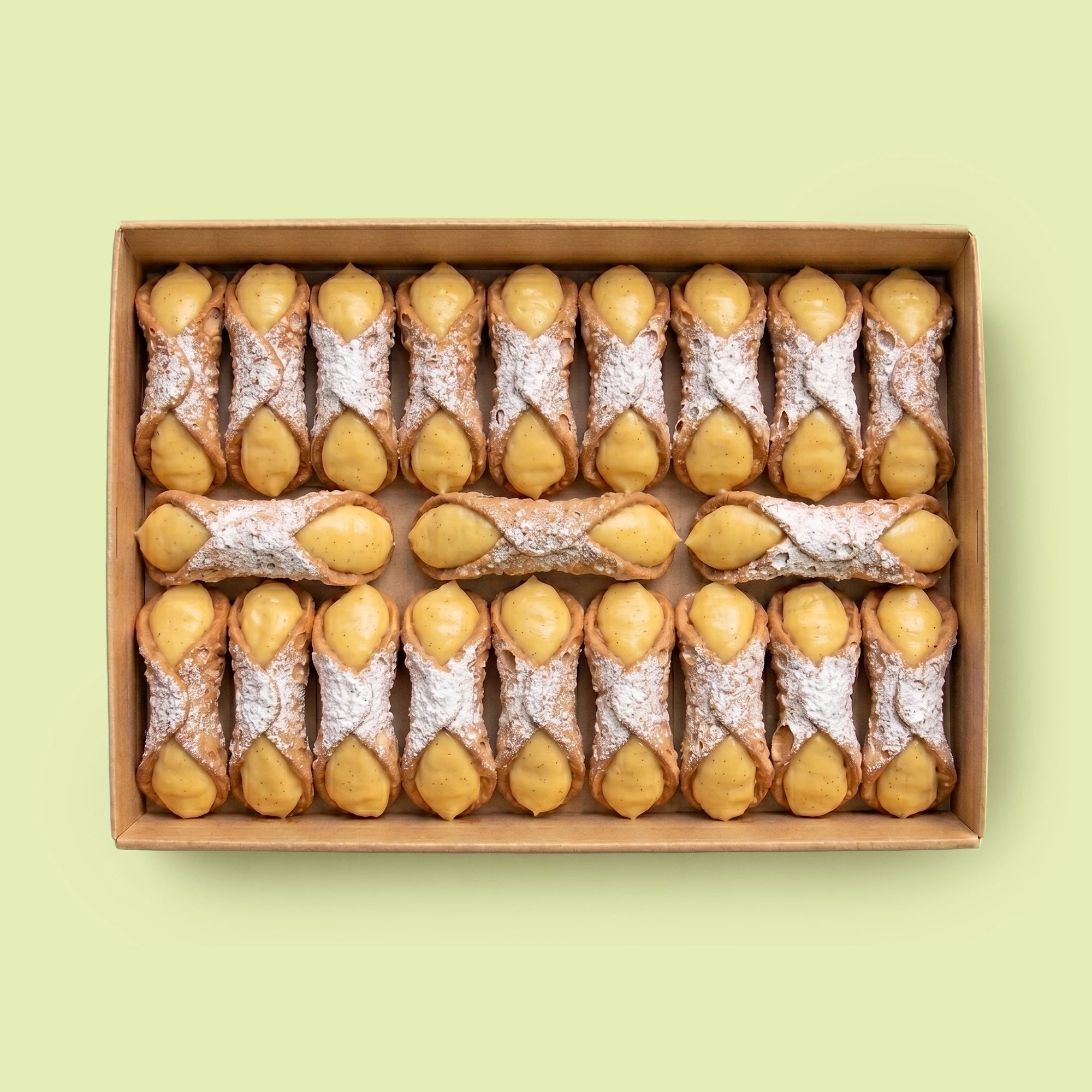 Box of cannoli filled with Vanilla Custard Cream on a light green background