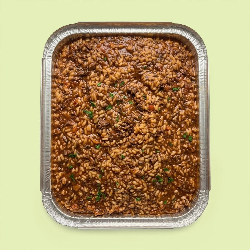 Risotto al Braised Beef Ragù in a catering tray, slow-cooked Arborio risotto with rich braised beef ragù and fresh parsley.