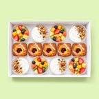 Breakfast catering box with eight pots of fresh fruit salad and Greek yoghurt with granola, and five mini Danish pastries with jam and custard.