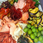 Platter of assorted meats, olives, and grilled vegetables on a white plate.