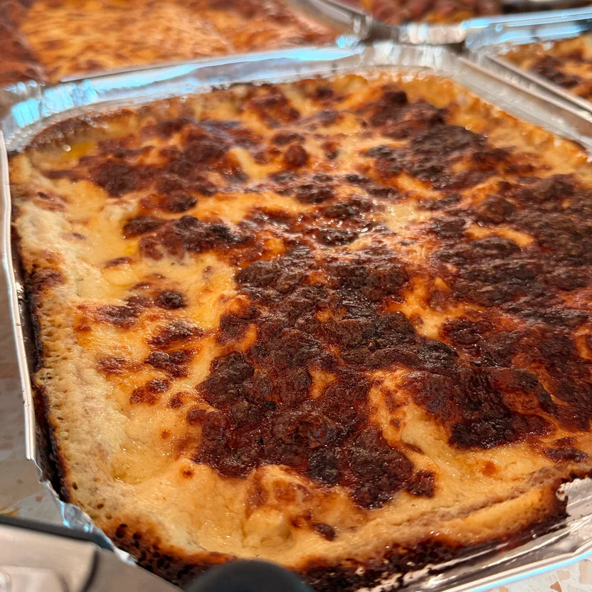 Array of multiple baked  lasagna in a metal foil tray displayed on a office catering