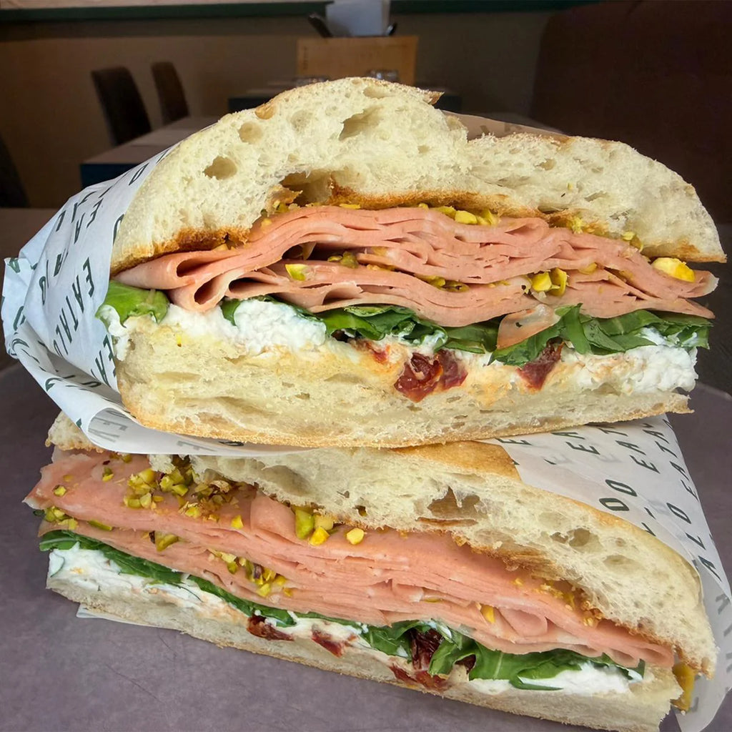 Half-cut sandwich with mortadella, lettuce, and burrata for office catering.