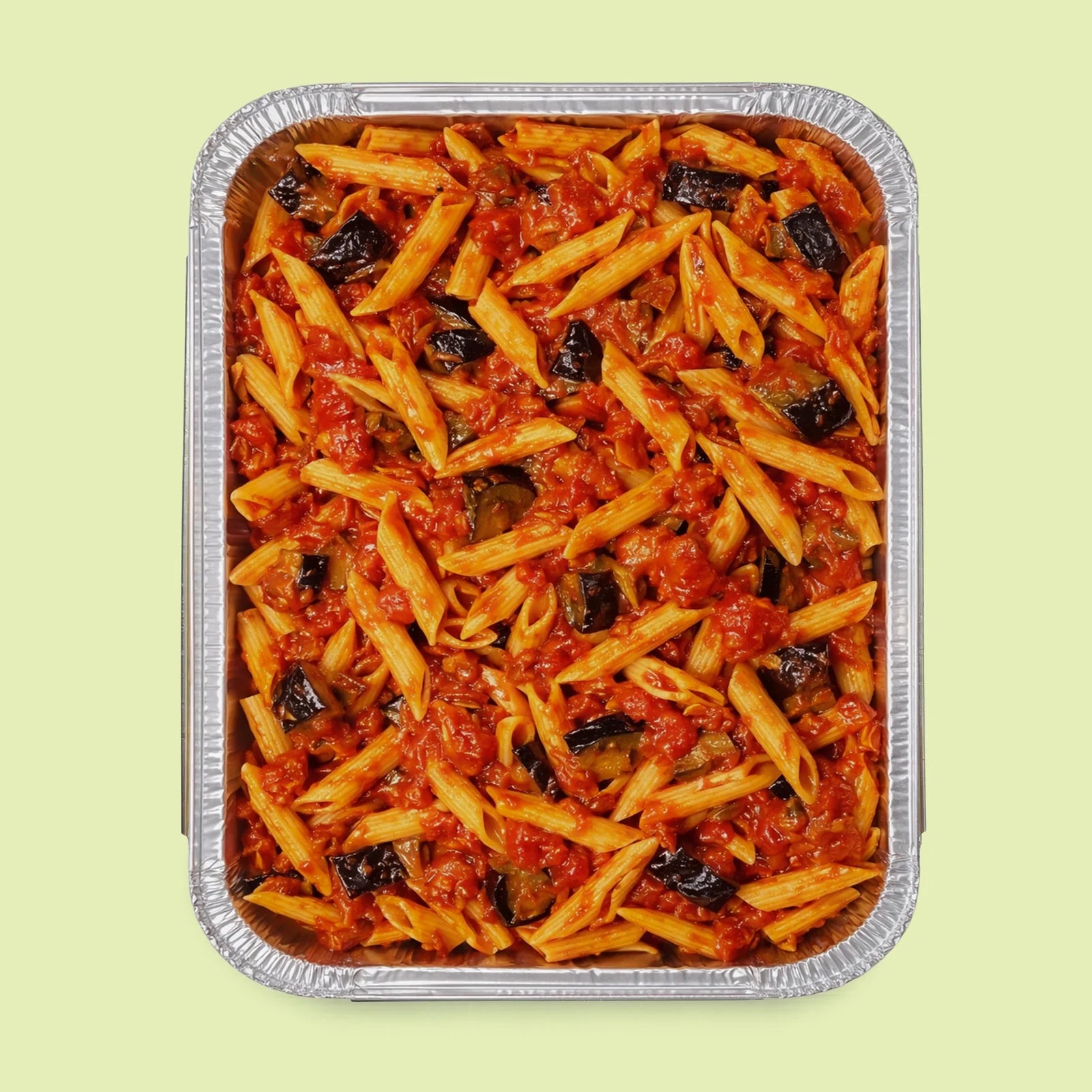 Aluminum tray of penne pasta with tomato sauce and eggplants on a light green background