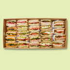 Large box of assorted Italian sandwiches on a light green background