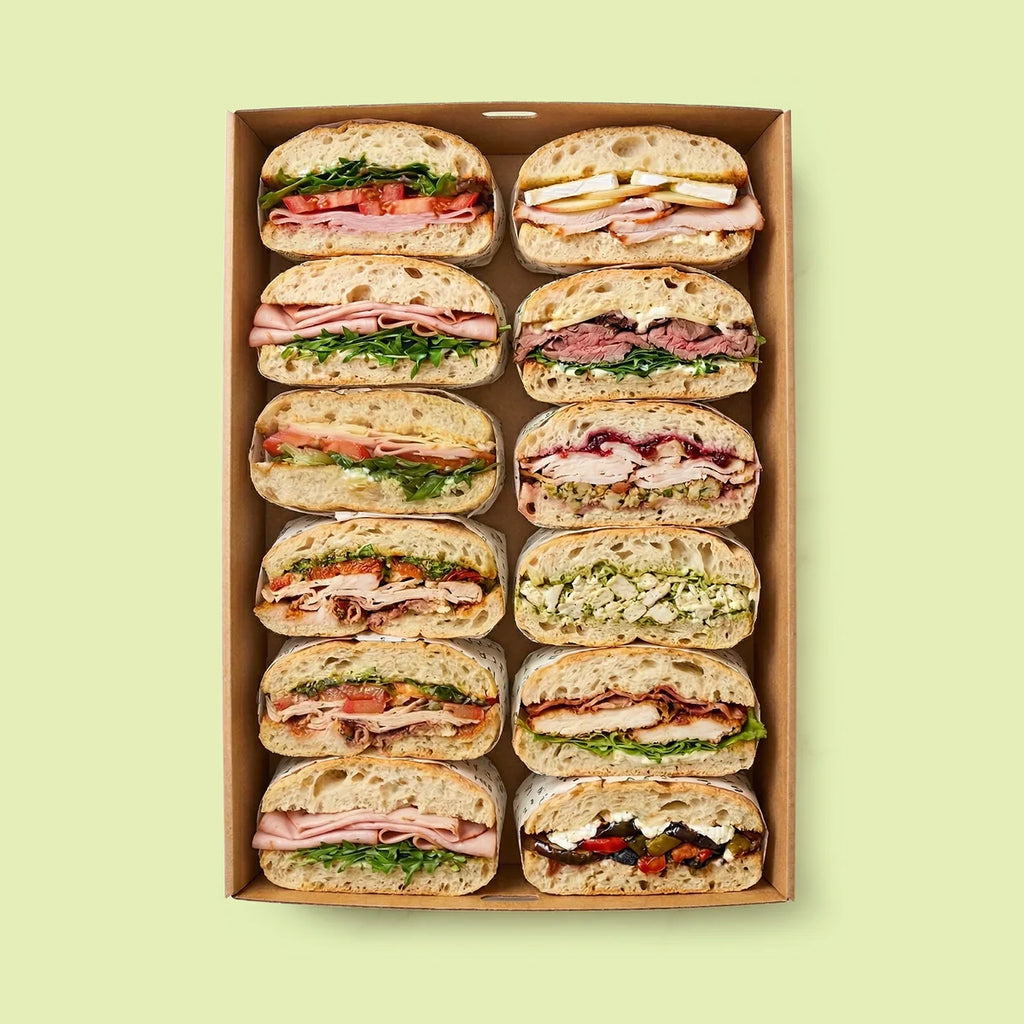 Box of pre-made Italian mix sandwiches on a light green background