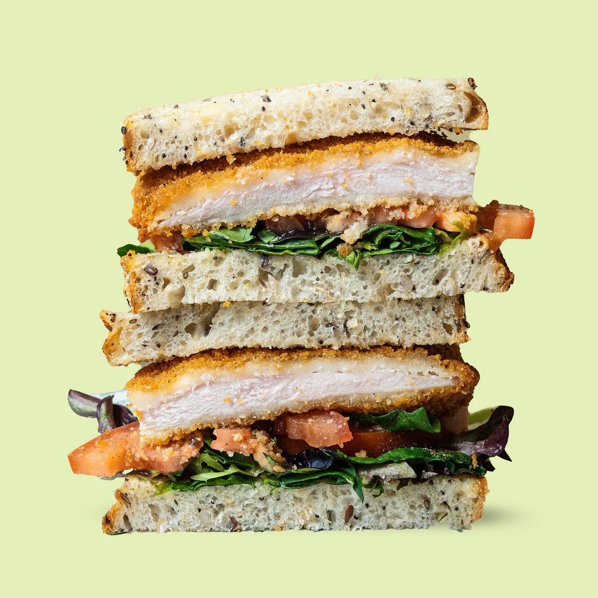 Stack of a sandwich with Chicken Schnitzel Sandwich on a light green background