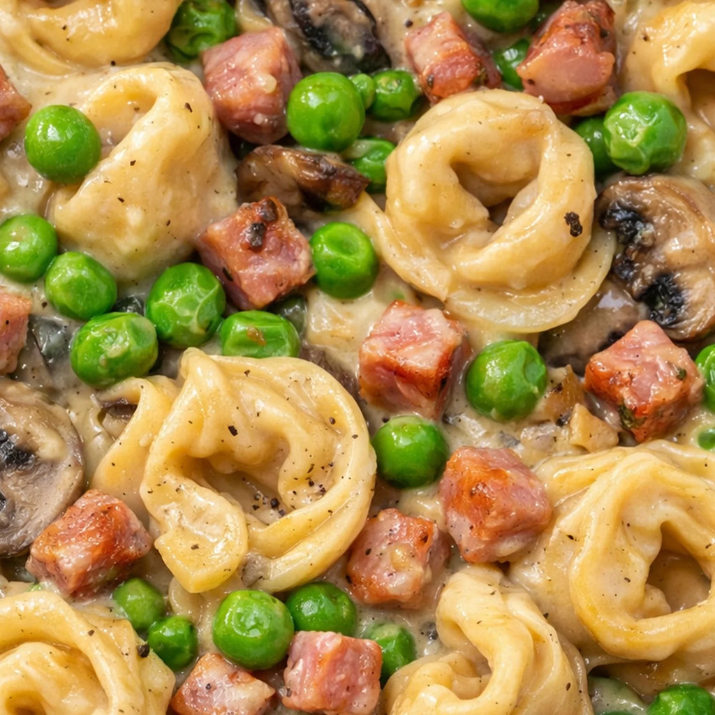 Close-up of creamy Italian tortellini pasta with creamy sauce of peas, mushroom and ham
