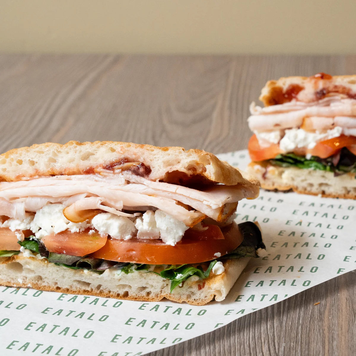 Turkey sandwich with tomato and cheese on a wooden surface
